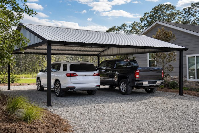 Steel carport sheltering vehicles on a driveway
